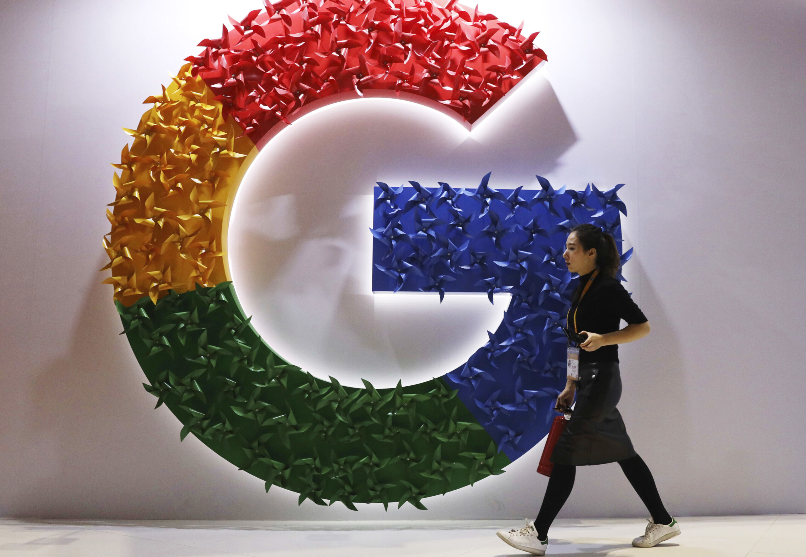 A woman walks past the logo for Google at the China International Import Expo in Shanghai